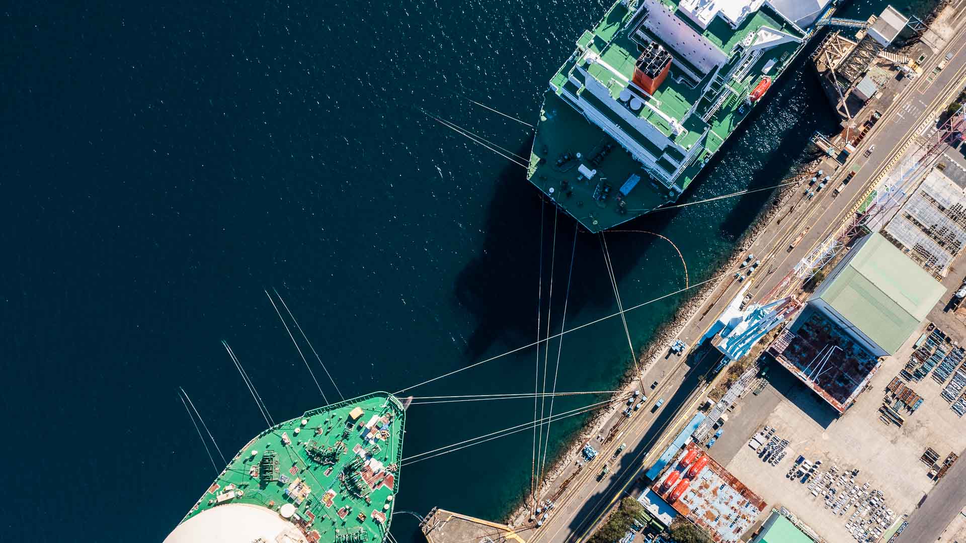 Top-down aerial view of two cargo vessels docked side by side at a quay, connected by mooring lines—emphasizing precision berthing, infrastructure coordination, and real-time situational awareness in port operations.